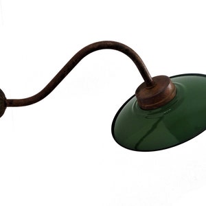 May include: A green metal wall sconce with a curved arm and a round base. The sconce has a rustic, industrial look.