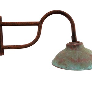 May include: A rusty metal wall sconce with a curved arm and a green copper-colored lampshade.