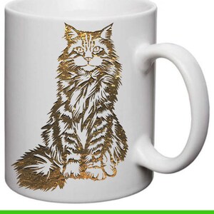 May include: White ceramic mug with a gold-colored illustration of a Maine Coon cat sitting on its haunches.