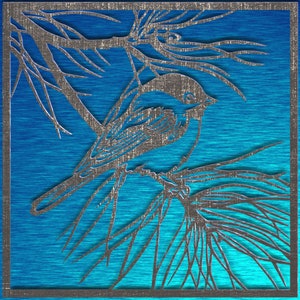 May include: A silver-colored, laser-cut bird perched on a branch, set against a vibrant blue background. The artwork features intricate details of the bird and foliage, framed within a square border. The design has a textured, metallic appearance.