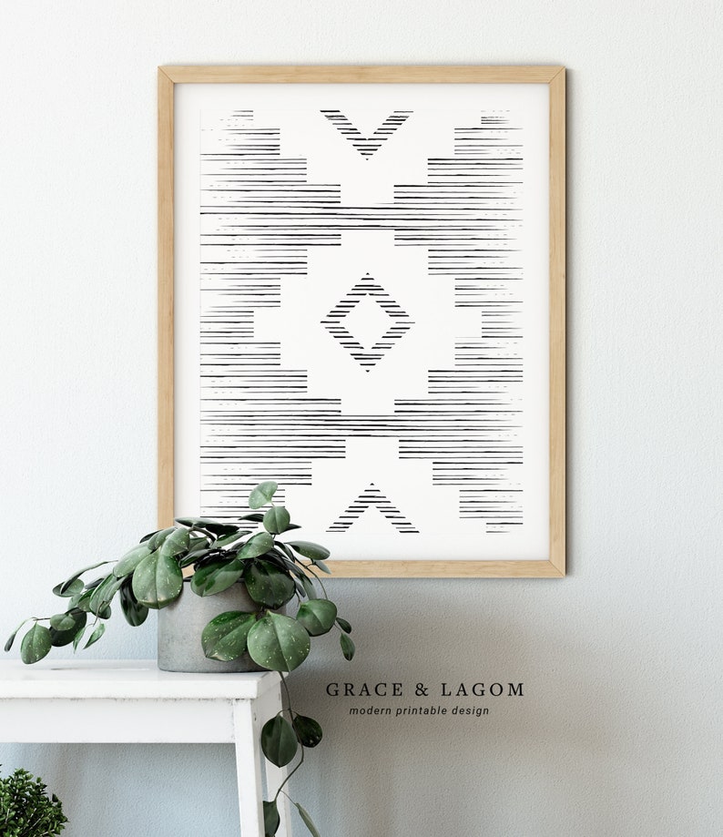 May include: A framed black and white geometric print with a light wood frame. The print features a symmetrical design of horizontal and angled lines. The text "GRACE & LAGOM modern printable design" is at the bottom.