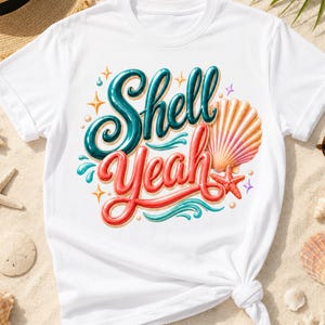 May include: White t-shirt featuring the phrase "Shell Yeah" in teal and red, with a seashell and starfish graphic. The design includes sparkling accents and a wave element, evoking a beach theme.