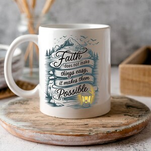 May include: White ceramic coffee mug with a blue and white design featuring a mountain scene and the text "Faith does not make things easy, it makes them possible".