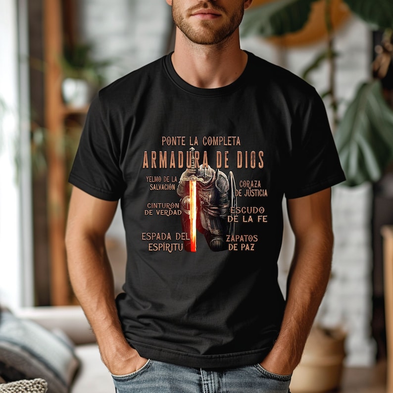 May include: Black t-shirt with a graphic of a knight in armor and the text "PONTE LA COMPLETA ARMADURA DE DIOS" in Spanish. The text below the graphic lists the different parts of the armor, including "YELMO DE LA SALVACI&Oacute;N", "CORAZA DE JUSTICIA", "CINTURON DE VERDAD", "ESCUDO DE LA FE", "ESPADA DEL ESP&Iacute;RITU", and "ZAPATOS DE PAZ".