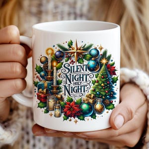 May include: White ceramic mug featuring a festive Christmas design. The design includes a wreath with ornaments, a Christmas tree, candles, and the text "Silent Night Holy Night". The mug is held by a person.