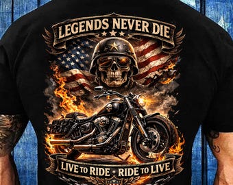 May include: Black t-shirt featuring a motorcycle design with a skull wearing a helmet, an American flag, and the text "LEGENDS NEVER DIE" and "LIVE TO RIDE • RIDE TO LIVE". The design incorporates flames and a chain border.