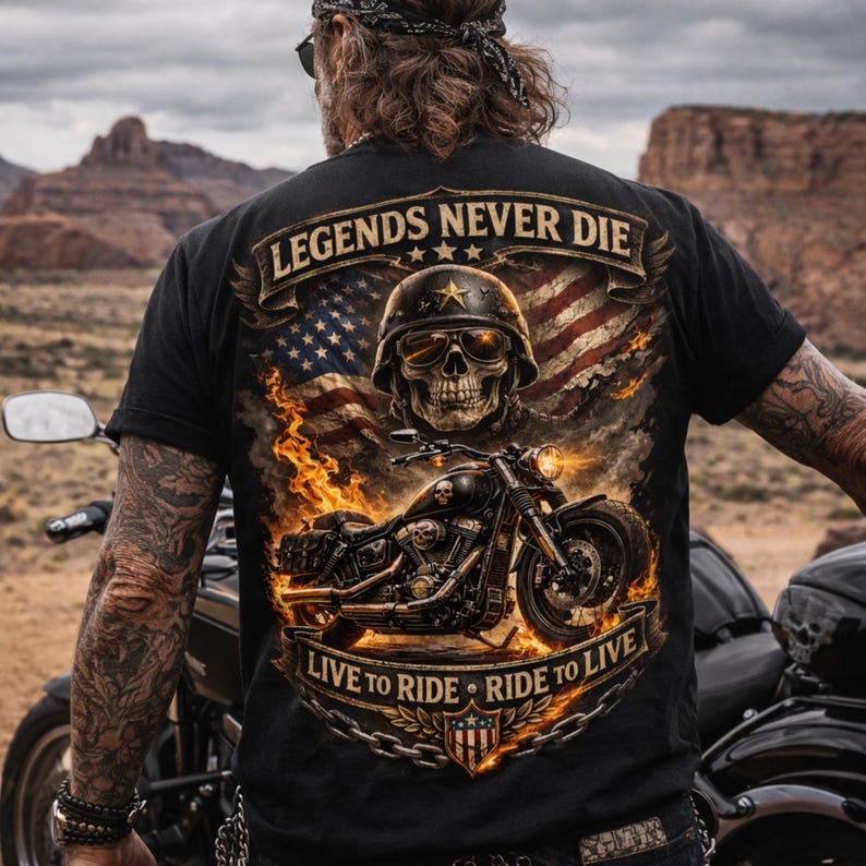 May include: Black t-shirt featuring a motorcycle graphic with a skull wearing a helmet and sunglasses, set against an American flag and flames. The text "LEGENDS NEVER DIE" and "LIVE TO RIDE - RIDE TO LIVE" are displayed on the shirt.