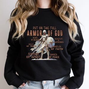 May include: Black sweatshirt featuring a graphic of a knight in armour and the text "Put on the full Armour of God" with the different parts of the armour labelled.
