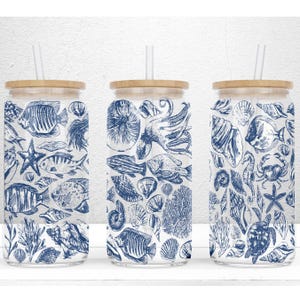 May include: Three clear glass tumblers with bamboo lids and blue and white nautical illustrations of sea life, including fish, seashells, starfish, and an octopus. Each tumbler has a straw.