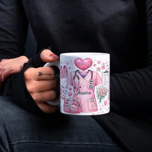 Puede incluir: Una taza de cer&aacute;mica blanca con un asa negra y el texto "But First, Coffee" en negrita negra. La taza se encuentra sobre un fondo borroso, sugiriendo un ambiente acogedor.