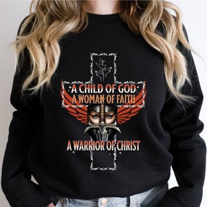 May include: Black sweatshirt with a graphic of a woman wearing a helmet and wings, with a cross behind her. The text on the graphic reads "A Child of God, A Woman of Faith, A Warrior of Christ."