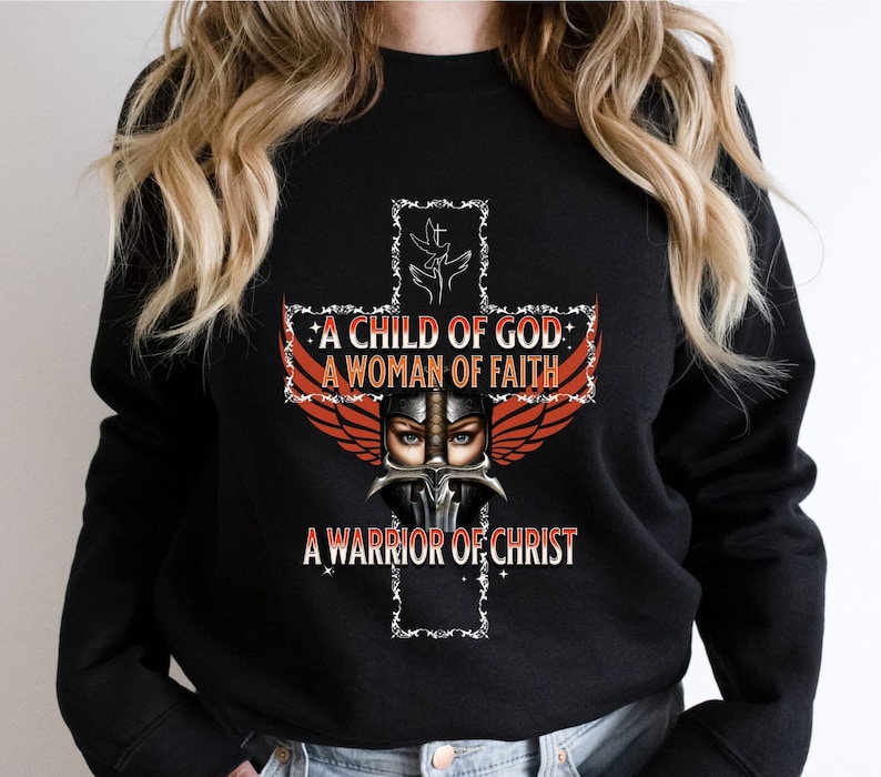 May include: Black sweatshirt with a graphic of a woman wearing a helmet and wings, with a cross behind her. The text on the graphic reads "A Child of God, A Woman of Faith, A Warrior of Christ."