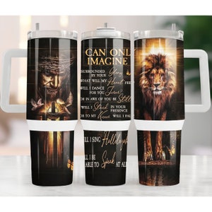 May include: A stainless steel tumbler with a white lid and handle. The tumbler features a black background with a golden cross, a lion, and a man with a crown of thorns. The text on the tumbler reads "Can Only Imagine" and includes lyrics from the song "Can Only Imagine" by the band MercyMe.