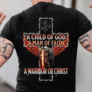 May include: A black t-shirt with a red and orange cross design. The cross features a knight holding a sword, two doves, and the text "A Child of God, A Man of Faith, A Warrior of Christ".