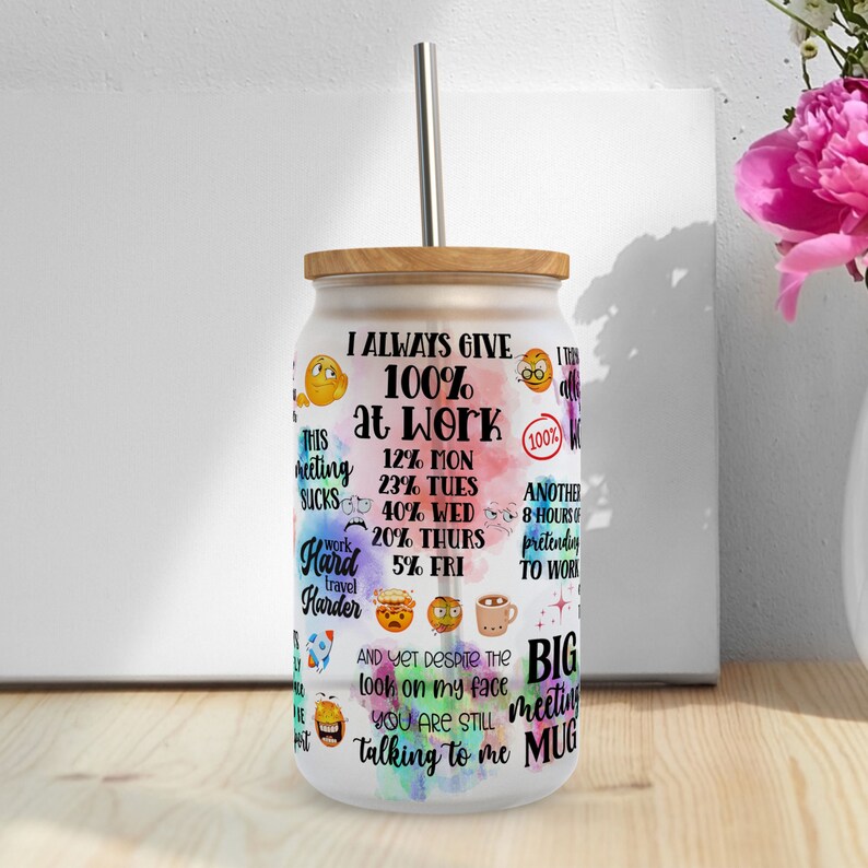 May include: A clear glass mug with a wooden lid and a straw. The mug has a colorful design with the text "I always give 100% at work" and other humorous phrases. The mug is a big meeting mug.