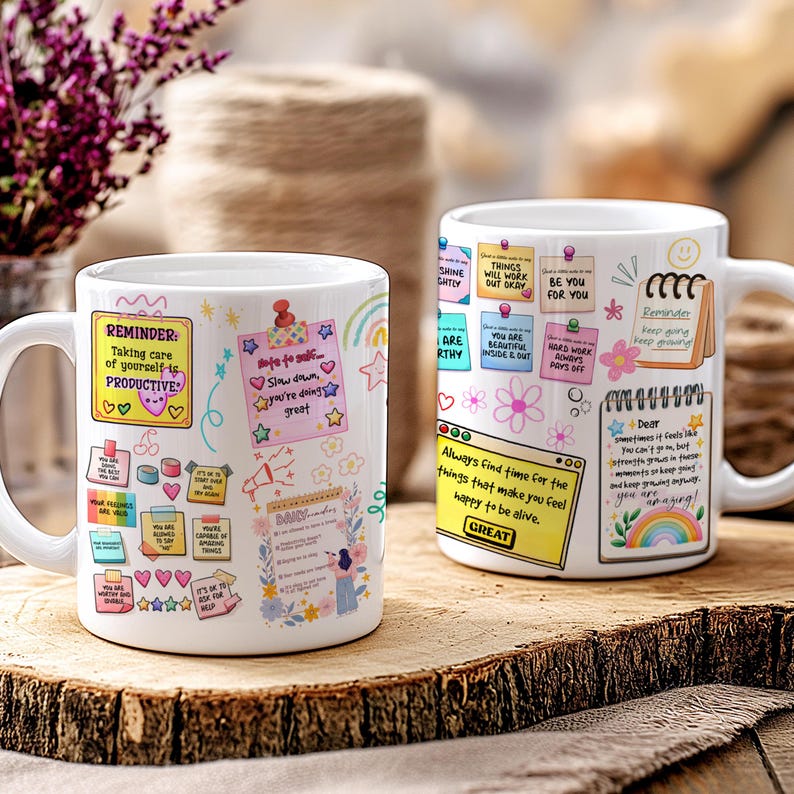May include: Two white ceramic mugs with colorful motivational notes and illustrations. One mug features the text "Reminder: Taking care of yourself is PRODUCTIVE." The other mug has the text "Always find time for the things that make you feel happy to be alive."