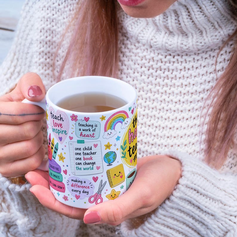 May include: White ceramic mug with colorful illustrations and text. The mug features a rainbow, hearts, stars, and the words "teach love inspire." Other text includes "teaching is a work of heart" and "one child one teacher one book can change the world."