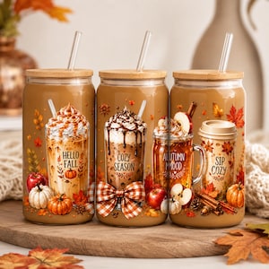 May include: Three glass tumblers with bamboo lids and clear straws, each featuring autumn-themed graphics of coffee drinks, pumpkins, apples, and fall leaves. The designs include text reading Hello Fall, Cozy Season, Autumn Mood, and Sip Cozy.