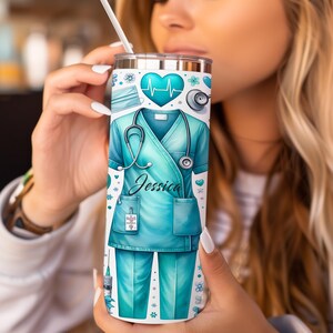 Peut inclure: Un gobelet en acier inoxydable avec un motif de blouse m&eacute;dicale turquoise, comprenant un st&eacute;thoscope, un moniteur de fr&eacute;quence cardiaque et le nom "Jessica". Le gobelet a un fond blanc avec des motifs floraux et m&eacute;dicaux.