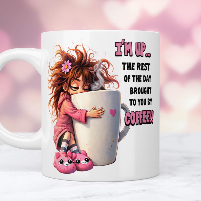 K&ouml;nnte beinhalten: Wei&szlig;e Keramik-Kaffeetasse mit einer Cartoon-Illustration einer schl&auml;frigen Person, die eine gro&szlig;e Kaffeetasse umarmt. Auf der Tasse steht der Text "I'M UP... THE REST OF THE DAY BROUGHT TO YOU BY COFFEE!!"