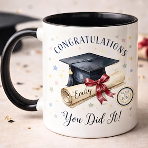 May include: White ceramic mug with a black handle and interior. The mug features a graduation cap, diploma, and the text "Congratulations You Did It!" with the name "Emily" and "Class of 2026".