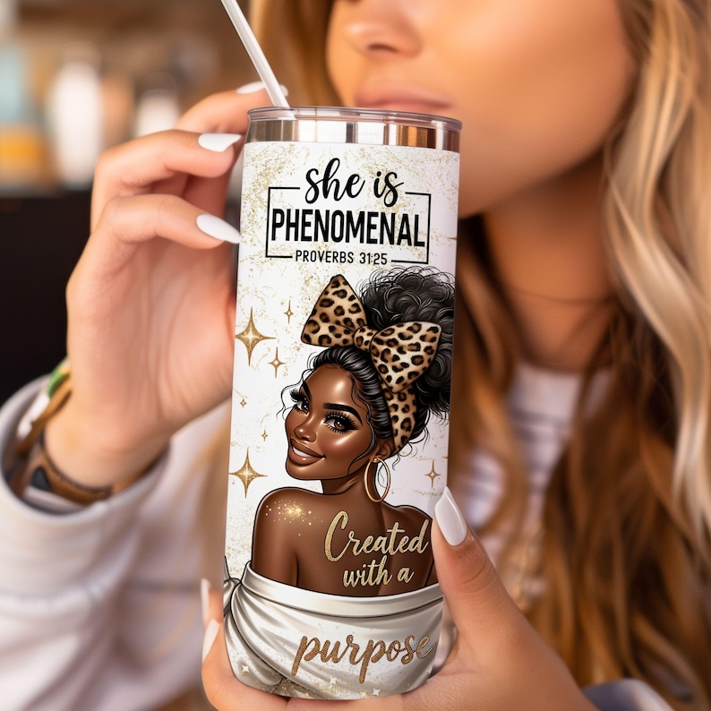 K&ouml;nnte beinhalten: Ein wei&szlig;er Becher mit goldfarbenem Glitzerhintergrund und einer schwarzen und braunen Illustration einer Frau mit einer Schleife im Leopardenmuster. Der Text auf dem Becher lautet "She is Phenomenal - Proverbs 31:25 Created with a purpose".