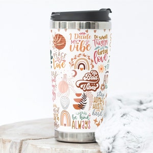 May include: A stainless steel travel mug with a white background and colorful graphics. The graphics include text such as "I Decide My Vibe", "Do Small Things With Great Love", "No Bad Vibes", "Stay Humble Hustle Hard", and "Be Kind Always".