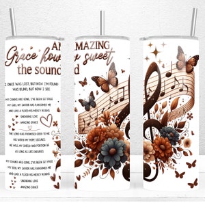 May include: A white tumbler with a brown and white floral design and a musical note. The tumbler has the text "Amazing Grace how sweet the sound" on it.