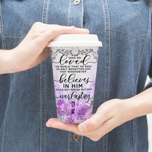 May include: A white travel mug with a purple floral design and the text "For God so loved the world that he gave his only begotten son that whosoever believes in him should not perish but have everlasting life".
