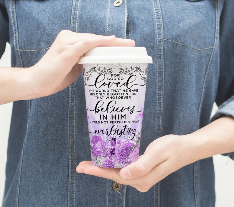 May include: A white travel mug with a purple floral design and the text "For God so loved the world that he gave his only begotten son that whosoever believes in him should not perish but have everlasting life".