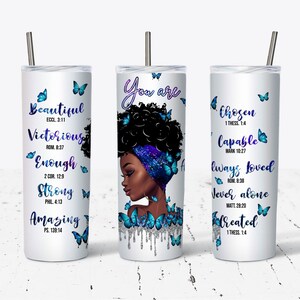 May include: Three white tumblers with stainless steel straws. Each tumbler features a different inspirational quote with bible verses and a black woman with blue butterflies. The first tumbler says "Beautiful, Victorious, Enough, Strong, Amazing" with bible verses. The second tumbler says "You are" with a black woman with blue butterflies. The third tumbler says "Chosen, Capable, Always Loved, Never Alone, Created" with bible verses.