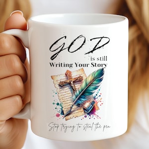 Create a meaningful Christian mug with this God Is Still Writing Your Story design. Featuring a cross, feather, and quill, it's perfect for inspirational gifts and daily reminders of faith.