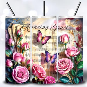 May include: Three stainless steel tumblers with black straws. Each tumbler features a design with pink roses, butterflies, and musical notes. The words "Amazing Grace" are written across the center tumbler.