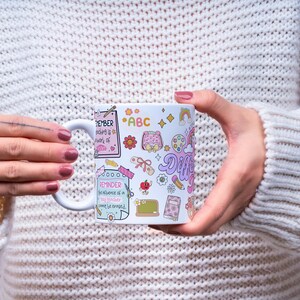 Pode incluir: Caneca de cer&acirc;mica branca com ilustra&ccedil;&otilde;es coloridas e texto. A caneca apresenta desenhos de material escolar, flores e arco-&iacute;ris. O texto inclui "REMEMBER teaching is a work of heart" e "REMINDER: the influence of a good teacher cannot be erased."