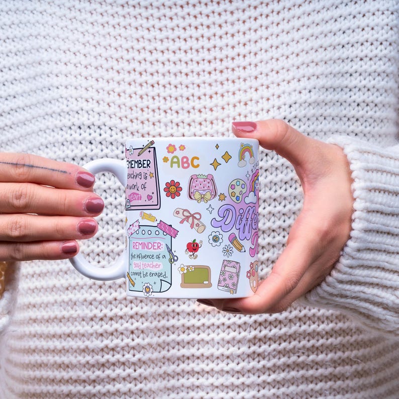 Pode incluir: Caneca de cer&acirc;mica branca com ilustra&ccedil;&otilde;es coloridas e texto. A caneca apresenta desenhos de material escolar, flores e arco-&iacute;ris. O texto inclui "REMEMBER teaching is a work of heart" e "REMINDER: the influence of a good teacher cannot be erased."