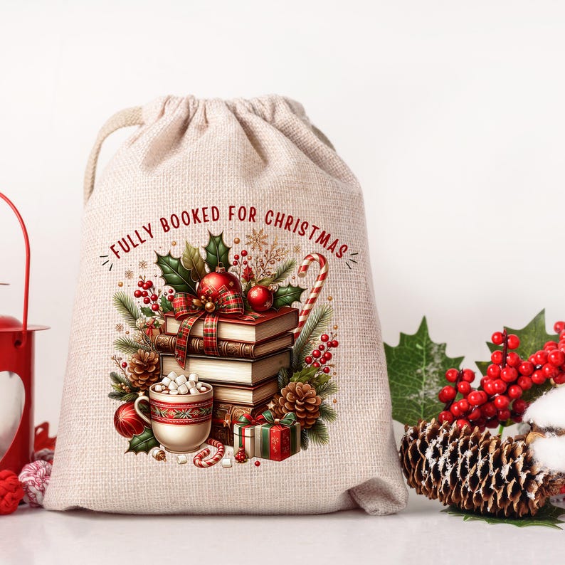 Op de afbeelding: Een beige geschenkzak met trekkoord met de tekst "FULLY BOOKED FOR CHRISTMAS" in het rood. De tas heeft een feestelijk ontwerp met boeken, ornamenten, hulst, een zuurstok en een kopje warme chocolademelk. Perfect voor kerstcadeaus.