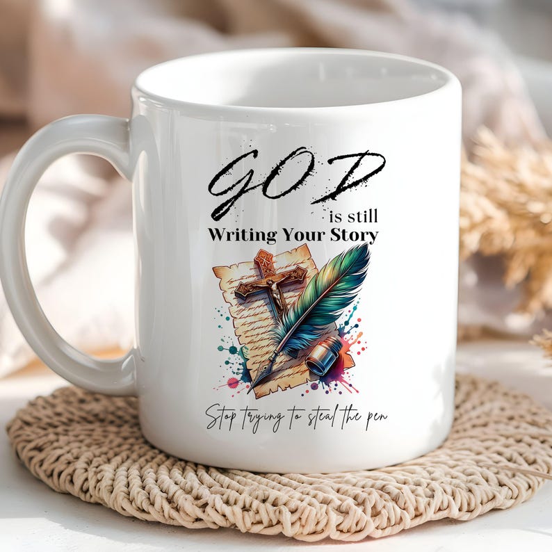 Puede incluir: Taza de cer&aacute;mica blanca con un dise&ntilde;o colorido que presenta una pluma estilogr&aacute;fica, una cruz y un rollo. El texto dice "GOD is still Writing Your Story Stop trying to steal the pen."