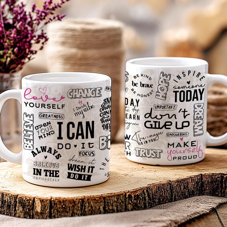 May include: Two white ceramic mugs with black and pink text. One mug says "I CAN" with other words like "Believe" and "Do It". The other mug says "Don't Give Up" and "Inspire Today". The mugs sit on a wooden surface.