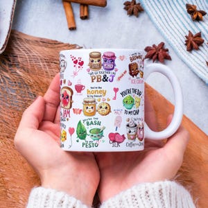 May include: White ceramic mug with a wraparound design featuring food-themed illustrations and phrases like "PB&J", "honey to my biscuit", and "You're the dip to my chip". The mug has a large, curved handle.