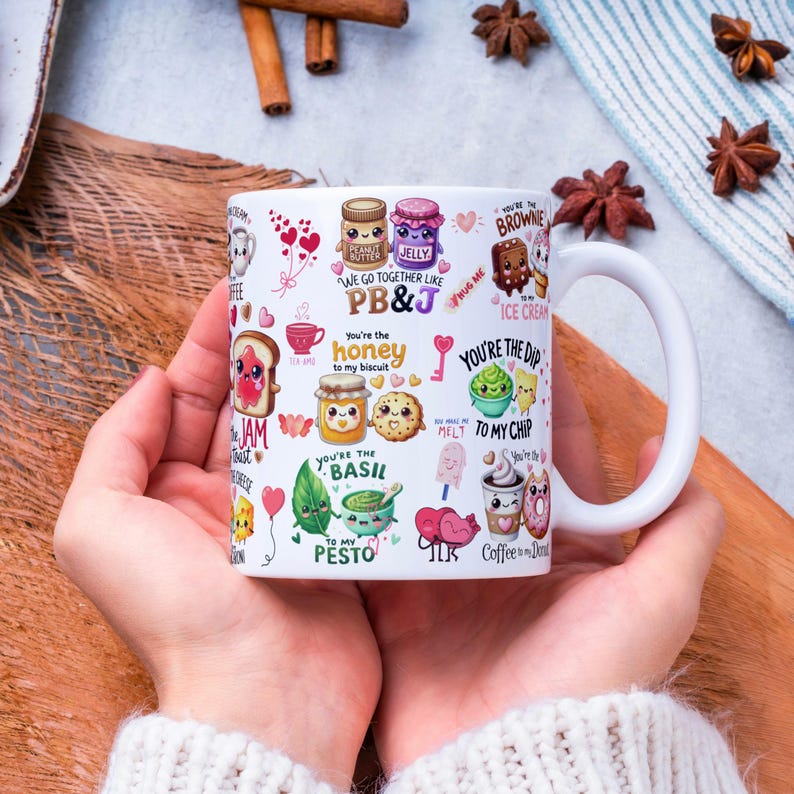 May include: White ceramic mug with a wraparound design featuring food-themed illustrations and phrases like "PB&J", "honey to my biscuit", and "You're the dip to my chip". The mug has a large, curved handle.