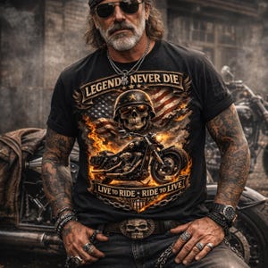 May include: Black t-shirt with a motorcycle graphic, a skull wearing a helmet, and the text "LEGEND NEVER DIE" and "LIVE TO RIDE &bull; RIDE TO LIVE". The design includes an American flag and flames. The person is wearing a belt with a skull buckle.