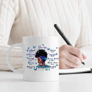 May include: White ceramic mug with a black and blue illustration of a woman with an afro and butterflies. The mug has the text "You are" and several words with bible verses, including "Beautiful", "Victorious", "Chosen", "Capable", "Enough", "Always Loved", "Never Alone", "Strong", "Amazing", and "Created".