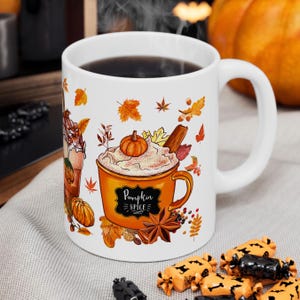 May include: White ceramic mug with a pumpkin spice design. The mug features an orange cup with whipped cream, a pumpkin, and a cinnamon stick. The words "Pumpkin Spice" are written on the cup. Autumn leaves and pumpkins are also featured.