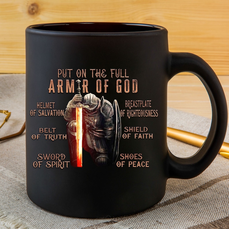 May include: Black ceramic coffee mug with a graphic of a knight in armor holding a sword. The text "Put on the full armor of God" is printed on the mug, along with the words "Helmet of Salvation", "Breastplate of Righteousness", "Belt of Truth", "Shield of Faith", "Sword of Spirit", and "Shoes of Peace".