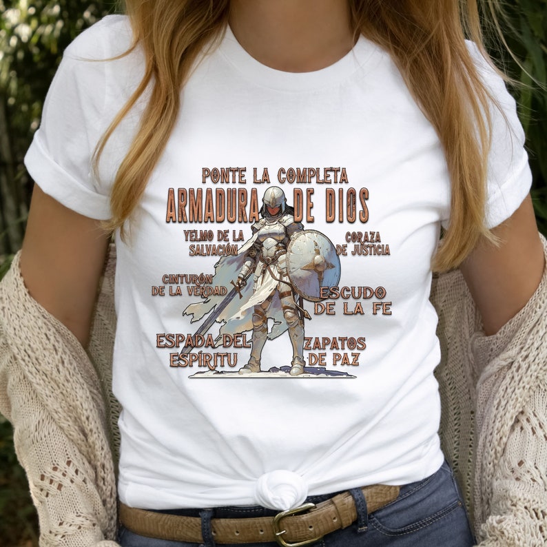 Pode incluir: Camiseta branca com um gr&aacute;fico de uma mulher com armadura, com o texto "PONTE LA COMPLETA ARMADURA DE DIOS" e uma lista de pe&ccedil;as de armadura em espanhol.