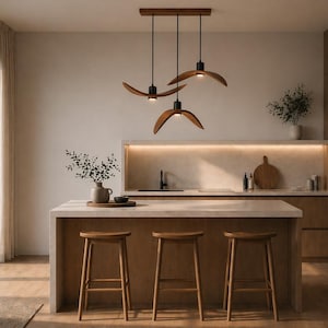 May include: A modern kitchen with a light wood island and three wooden pendant lights. The lights have a unique, curved design. Three wooden stools are positioned at the island. The kitchen also features a built-in oven and wooden cabinetry.