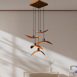 May include: A modern wooden chandelier with six curved, leaf-shaped light fixtures suspended from a square wooden ceiling mount. The lights are a warm brown color with black accents, creating a stylish and contemporary design.