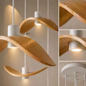 May include: Modern pendant lights with a curved, wooden shade and a white base. The lights hang from white cords and emit a warm glow. The wooden shades have a natural wood grain finish.