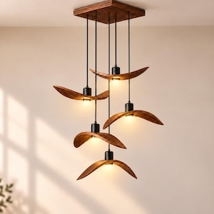 May include: A multi-light pendant chandelier featuring five curved, wood-grain finish shades suspended from a square wooden ceiling mount by black cords. Each shade houses a single light bulb, creating a tiered arrangement of warm illumination.