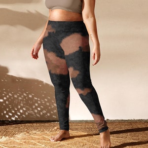May include: A person wearing a brown sports bra and black leggings with a tie-dye pattern. The leggings have a high waist and are fitted.
